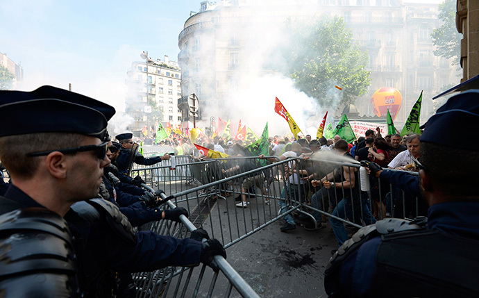 French riot police fire tear gas against protesters trying to move crowd control barriers during a demonstration by striking employees of the French state rail company SNCF near the Transport Ministry in Paris on June 12, 2014, on the second day of a nation-wide strike to protest a government railway reform project. (AFP Photo / Bertrand Guay)