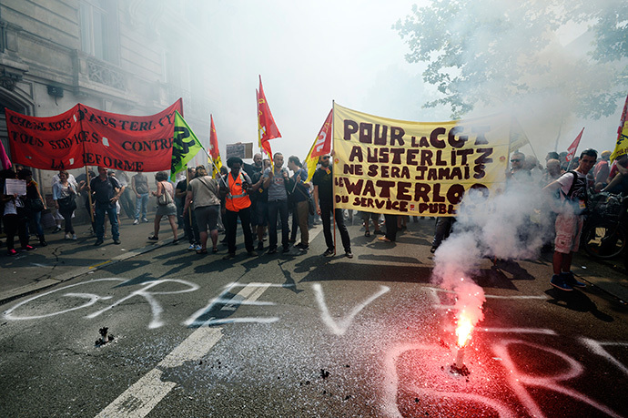 Protesters hold a banner behind a burning flare reading "For CGT, Austerlitz will never be the Waterloo of public service" during a demonstration by striking employees of the French state rail company SNCF near the Transport Ministry in Paris on June 12, 2014, on the second day of a nation-wide strike to protest a government railway reform project. (AFP Photo / Bertrand Guay)