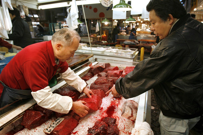  wholesaler (L) examines whale meat with a customer at the Tsukiji fish market in Tokyo (Reuters/Kiyoshi Ota)