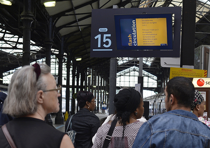 Travelers watch an information board announcing the trains that will be running, at the Gare Saint Lazare train station in Paris during a strike by SNCF railway company workers, on June 15, 2014. (AFP Photo / Miguel Medina)