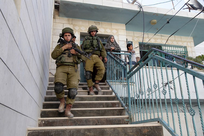 Israeli soldiers leave after inspecting a house where live Palestinians in the West Bank village of Tafoh, near Hebron on June 15, 2014, as they search for three teenagers who went missing near a West Bank settlement. (AFP Photo / Hazem Bader)