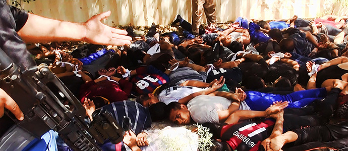  An image uploaded on June 14, 2014 on the jihadist website Welayat Salahuddin allegedly shows militants of the Islamic State of Iraq and the Levant (ISIL) standing next to dozens of captured Iraqi security forces members at an unknown location in the Salaheddin province ahead of executing them. (AFP Photo)