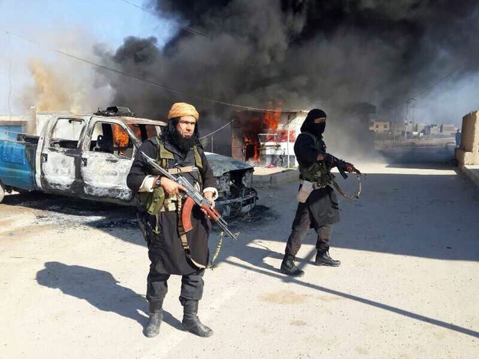Shakir Wahib (L), Abu Wahib, a leader of the Islamic State of Iraq and the Levant (ISIL) standing next to burning cars, at an undisclosed location in Iraq. (AFP Photo / HO / Hanein.info)