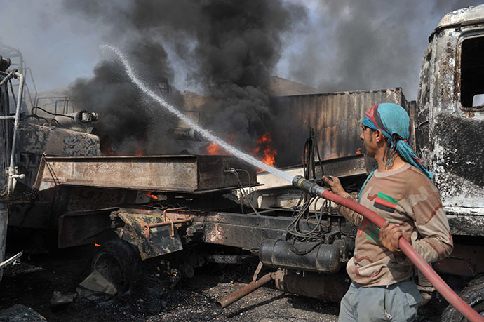 Afghan firefighters extinguish burning NATO military vehicles at the scene of a suicide attack at the Afghan-Pakistan border crossing in Torkham, Nangarhar province on June 19, 2014. (Reuters / Noorullah Shirzada)