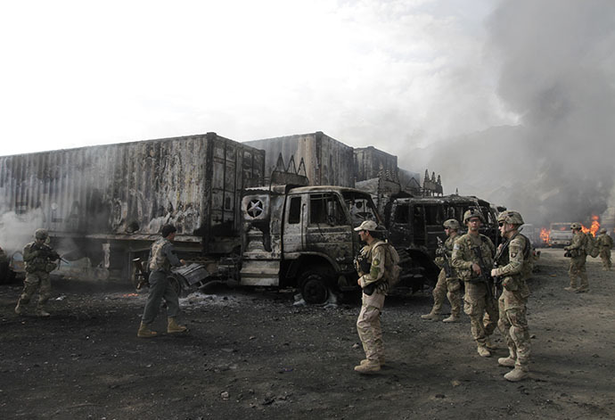 NATO troops walk near burning NATO supply trucks after, what police officials say, was an attack by militants in the Torkham area near the Pakistani-Afghan in Nangarhar Province June 19, 2014. (Reuters / Parwiz Parwiz)