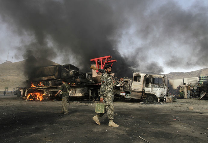Afghan security forces walk near burning NATO supply trucks after, what police officials say, was an attack by militants in the Torkham area near the Pakistani-Afghan in Nangarhar Province June 19, 2014. (Reuters / Parwiz Parwiz)