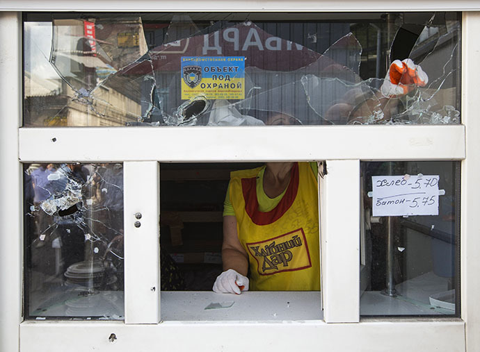 A bakery assistant removes broken glass from a window after overnight shelling on a market in the eastern Ukranian city of Slaviansk June 17, 2014. (Reuters / Shamil Zhumatov)