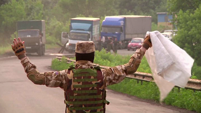 A Lugansk militiaman on road holding white flag, Ukrainian soldiers seen approaching from further down the road. Still from AP video