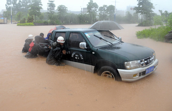 Rescue workers push a vehicle on a flooded street in Qinzhou, Guangxi Zhuang Autonomous Region, June 11, 2014. (Reuters)
