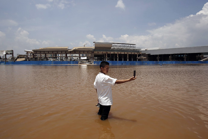A resident takes a picture of himself standing in flood waters at a flooded area of Wujiaba airport in Kunming, Yunnan province June 9, 2014. (Reuters)