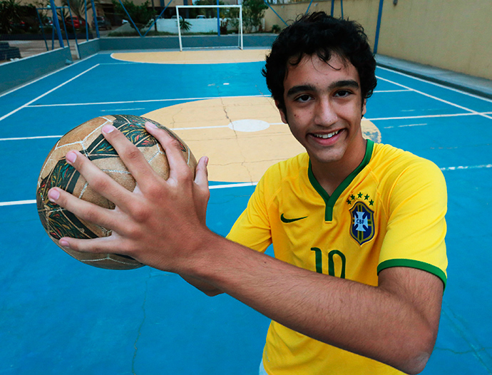 Joao de Assis, a member of the da Silva family with six relatives who all have six fingers on their hands, poses for a photo with a soccer ball at their home in Brasilia, June 20, 2014 (Reuters / Joedson Alves)