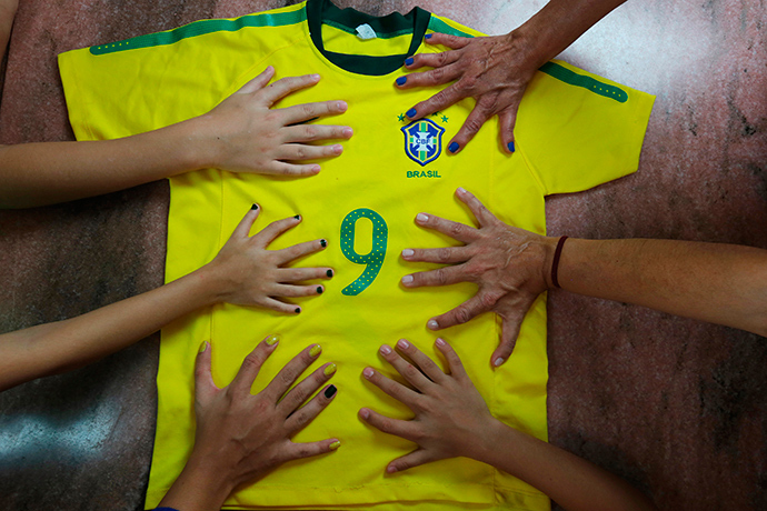Members of the da Silva family pose for a photo with a national soccer jersey showing their hands all have six fingers, in Brasilia, June 20, 2014 (Reuters / Joedson Alves)