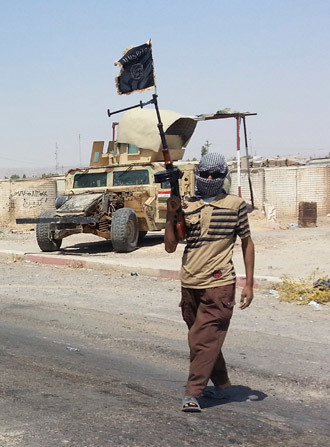 A fighter of the Islamic State of Iraq and the Levant (ISIL) stands guard at checkpoint near the city of Baiji, north of Baghdad (Reuters / Stringer)