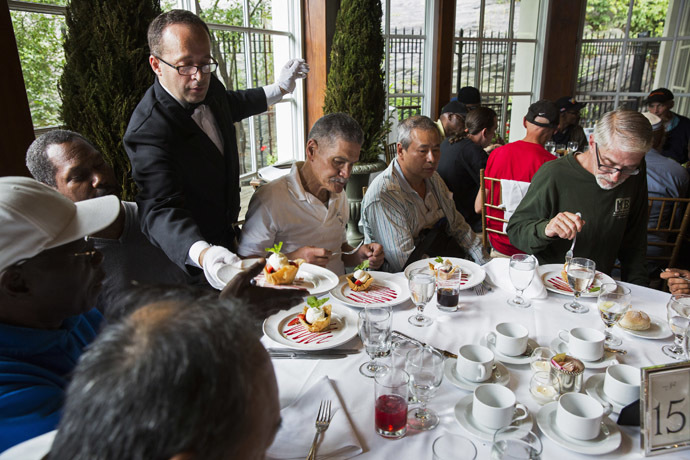 A waiter serves dessert to a table of men listening to Chinese millionaire Chen Guangbiao during a lunch he sponsored for hundreds of needy New Yorkers at Loeb Boathouse in New York's Central Park June 25, 2014. (Reuters/Lucas Jackson)