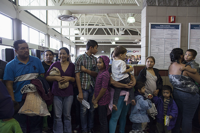 Migrants, consisting of mostly women and children, who just disembarked from a U.S. Immigration and Customs Enforcement (ICE) bus wait for a Greyhound official to process their tickets to their next destination at a Greyhound bus station in Phoenix, Arizona May 29, 2014. (Reuters / Samantha Sais)