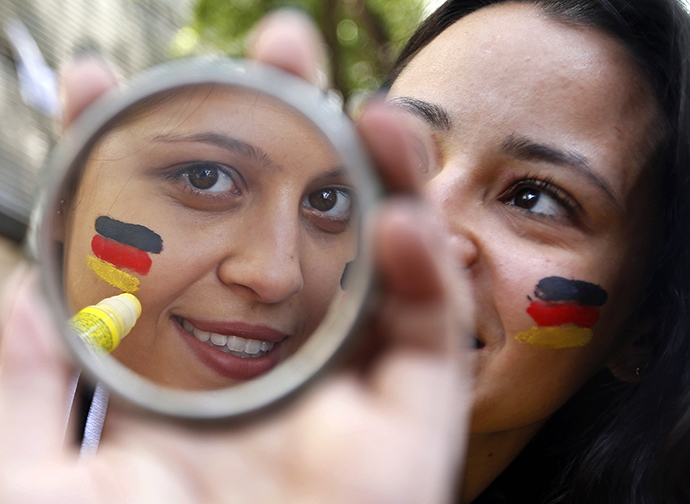 Stephanie, a fan supporting Germany's national soccer team, uses a stick to paint the German flag on her face before the broadcast of the 2014 World Cup Group G soccer match between the U.S. and Germany in Belo Horizonte June 26, 2014. (Reuters / Eric Gaillard)