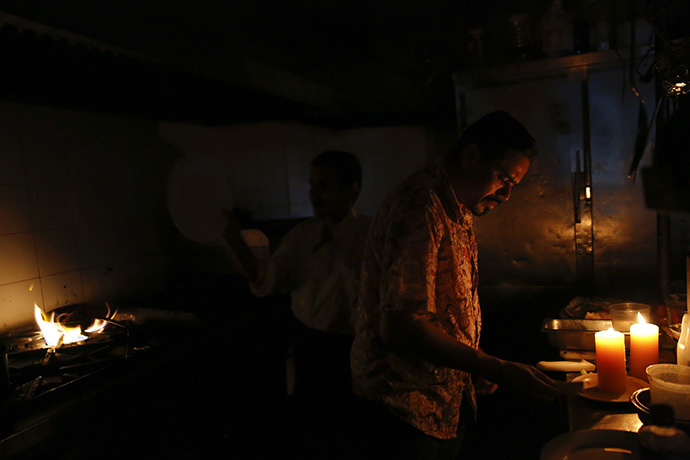 Restaurant workers try to finish up orders in the kitchen during a blackout in Caracas June 27, 2014. (Reuters / Carlos Garcia Rawlins)
