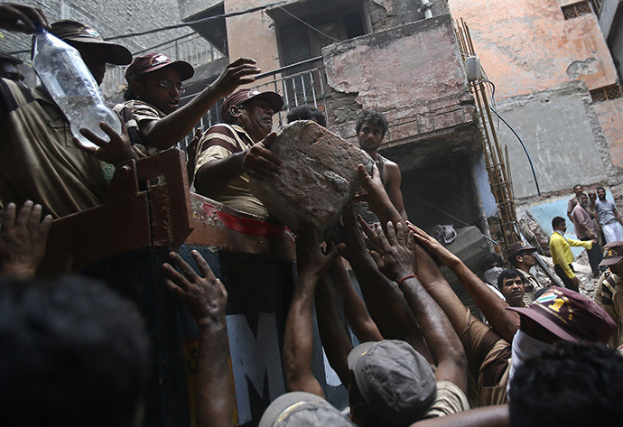 Rescue workers and volunteers load debris onto a truck at the site of a collapsed building in New Delhi June 28, 2014. (Reuters / Anindito Mukherjee)