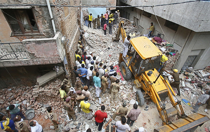Rescue workers and volunteers stand at the site of a collapsed building in New Delhi June 28, 2014. (Reuters / Anindito Mukherjee)