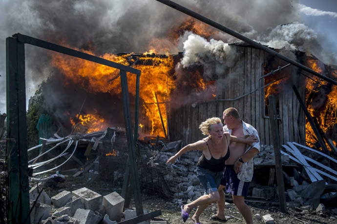 Local residents escape from a fire in the house destroyed in the Ukrainian armed forces' air attack on the village of Luganskaya on July 2, 2014 (RIA Novosti/Valeriy Melnikov)