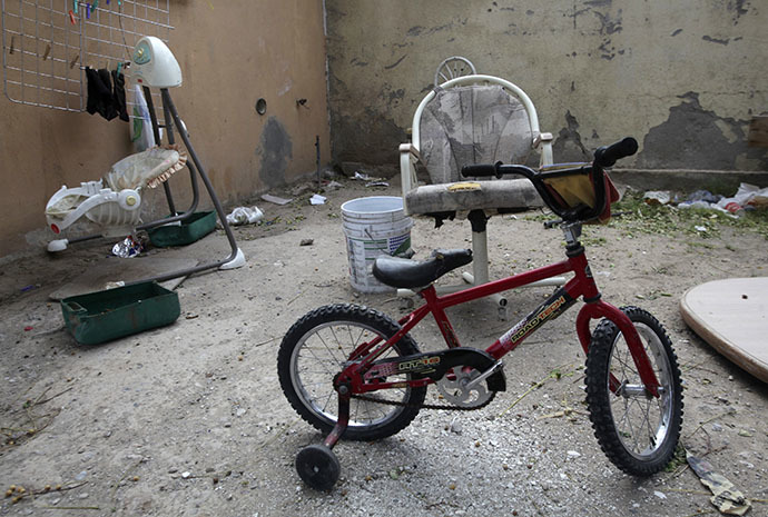 An abandoned bicycle for children, a baby swing and rubbish are seen in the back patio of a house seized by authorities in Ciudad Juarez May 23, 2014. (Reuters / Jose Luis Gonzalez)