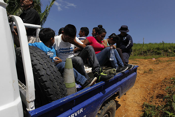 Unaccompanied minors and a family sit in the bed of a police truck after being detained for the lack of identity documents at a porous border known as La Montanita in the small village of Suyapa, on the border of Honduras with Guatemala June 20, 2014. (Reuters / Jorge Cabrera)