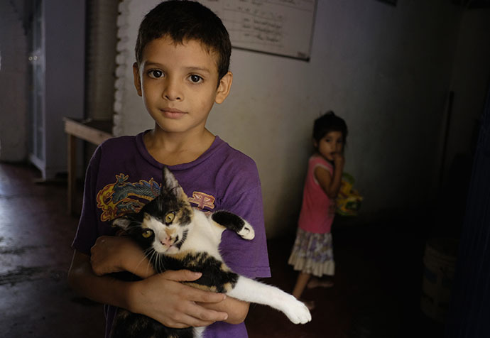 A Honduran child, who will be accompanied by his family when they travel to reach northern Mexico or the U.S., holds a cat as he poses for a picture at the Todo por ellos (All for them) immigrant shelter in Tapachula, Chiapas, in southern Mexico, June 26, 2014. (Reuters / Jorge Lopez)