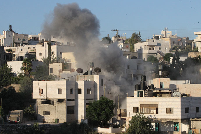 Smoke rises from the home of Ziad Awwad, 42, and his son Ezzedine Awwad, 18, after it was destroyed by the Israeli military, in the village of Idnah, close to the southern West Bank city of Hebron, on July 2, 2014. (AFP Photo / Hazem Bader)