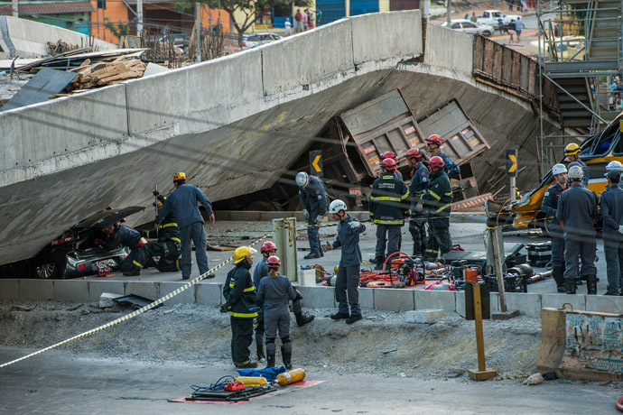 Firefighters and policemen work at the site where several vehicles were crushed by a viaduct that collapsed in Belo Horizonte, Brazil, on July 3, 2014. (AFP Photo/Pedro Duarte) 