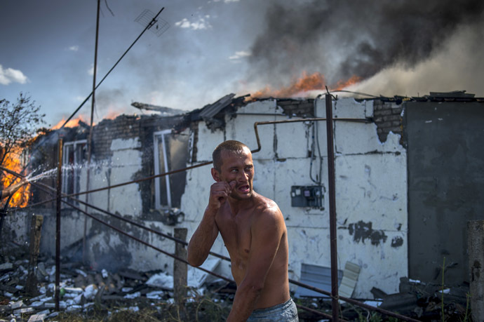 Local resident puts out the fire in a house damaged by an air strike by the Ukrainian armed forces on the village of Luganskaya. (RIA Novosti/Valeriy Melnikov)