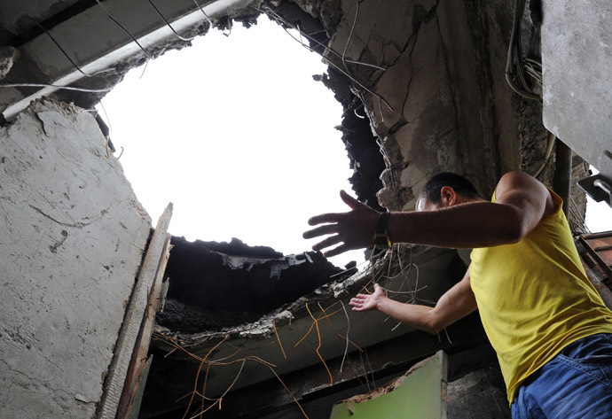 A resident looks at a hole on July 9, 2014 in the ceiling of his apartment, in a building damaged the day before by Ukrainian forces' mortar fire, in Lugansk, eastern Ukraine (AFP Photo)