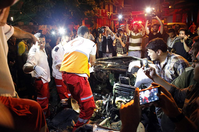 Palestinian rescuers check a car hit by an Israeli air strike killing the driver in Gaza City on July 9, 2014. (AFP Photo / Thomas Coex)