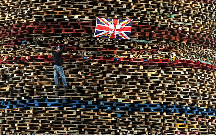 A man gestures as he climbs a bonfire on the Shankill Road in West Belfast July 10, 2014 (Reuters / Cathal McNaughton)