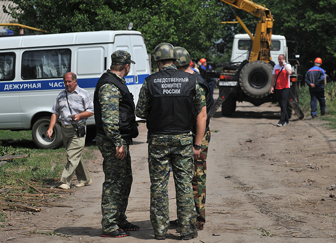 Law enforcement officers work at the area in the town of Donetsk in Russia's Rostov Region which was hit by a high-explosive shell fired from the Ukrainian territory, July 13, 2014. (RIA Novosti / Sergey Pivovarov)