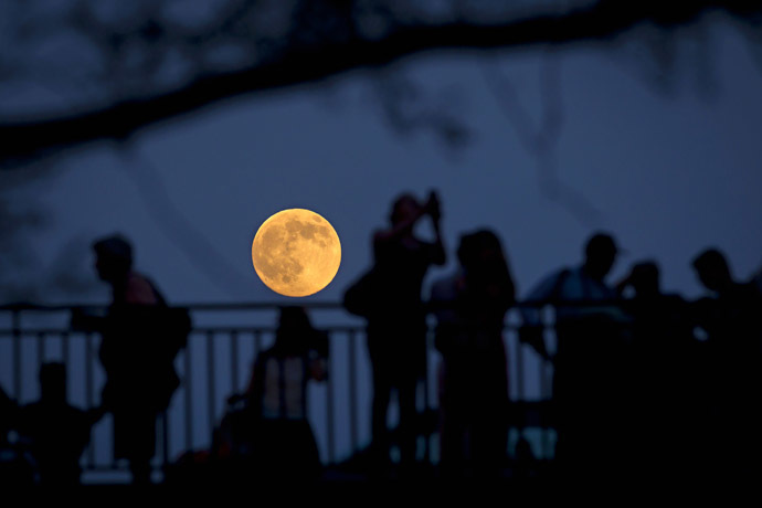 People stand and look at the moon one day ahead of the Supermoon phenomenon from a bridge over 42nd St. in the Manhattan borough of New York July 11, 2014 (Reuters/Carlo Allegri)