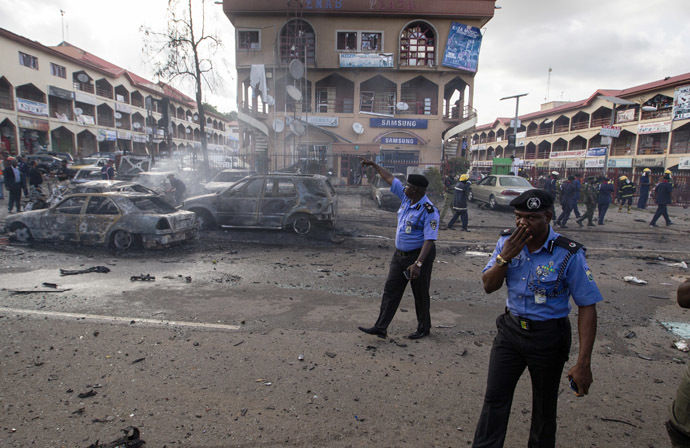 Policemen walk towards burnt vehicles at the scene of a blast at a business district in Abuja June 25, 2014. (Reuters/Afolabi Sotunde)