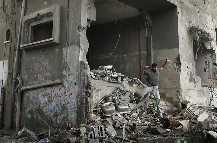 A Palestinian walks amidst the debris of a neighbouring house which police said was damaged after an Israeli air strike destroyed Tayseer Al-Batsh's family house, in Gaza City July 13, 2014. (Reuters / Mohammed Salem)