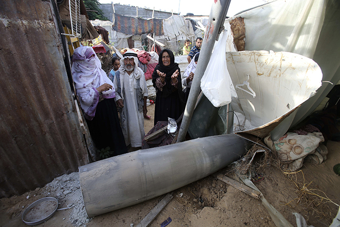 A Palestinian woman gestures as she stands behind a missile which witnesses said was fired by Israeli aircraft, at a shack belonging to Bedouins in Rafah, in the southern Gaza Strip July 13, 2014. (Reuters / Ibraheem Abu Mustafa)