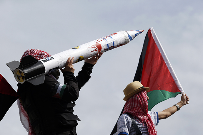 Protesters wearing kaffiyehs hold a Palestinian flag and a fake rocket with the Israeli flag, swastikas and a nuclear symbol on July 13, 2014 in Paris, during a demonstration against Israel and in support of residents in the Gaza Strip. (AFP Photo / Kenzo Tribouillard)