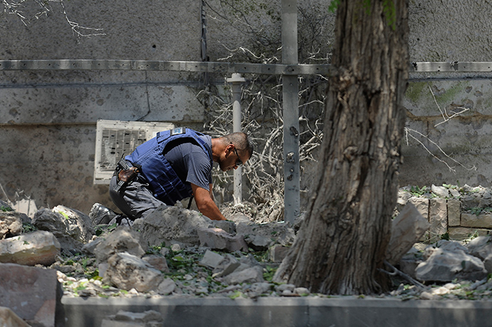 An Israeli bomb disposal expert inspects the remains of a rocket fired by Palestinian militants from the Gaza Strip that hit a yard outside a house in the southern port city of Ashdod on July 15, 2014 (AFP Photo / David Buimovich)