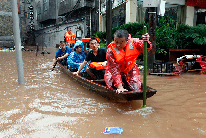 Rescuers evacuate residents and tourists with a boat on a flooded street of the ancient town as heavy rainfall hit Fenghuang county, Hunan province July 15, 2014 (Reuters / China Daily)