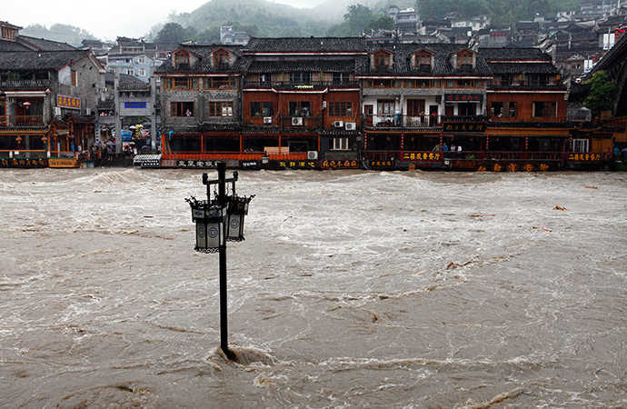 A street lamp is seen in floodwaters in front of partially submerged buildings by an overflowing river at the ancient town as heavy rainfall hits Fenghuang county, Hunan province July 15, 2014 (Reuters / China Daily)