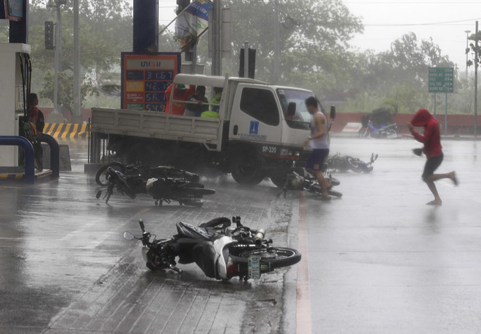 People run towards a gas station to take cover past fallen motorcycles on a main road after strong winds brought by Typhoon Rammasun, locally called Glenda, battered the capital, metro Manila July 16, 2014. (Reuters)
