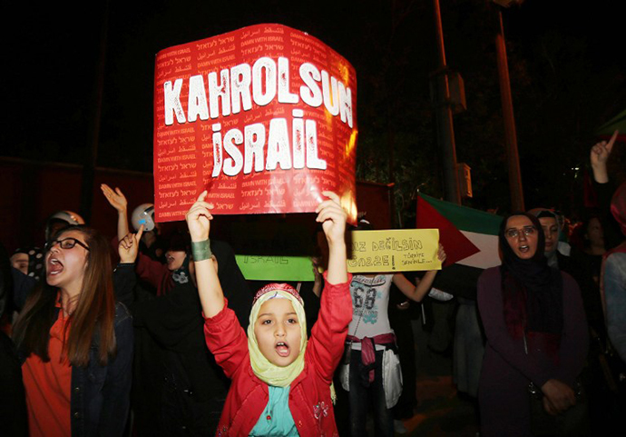 A girl holds a poster reading "God damns Israel" during a protest against Israel's military action in Gaza, in front of the Israelian Embassy in Ankara, on July 18, 2014. (AFP Photo / Adem Altan)