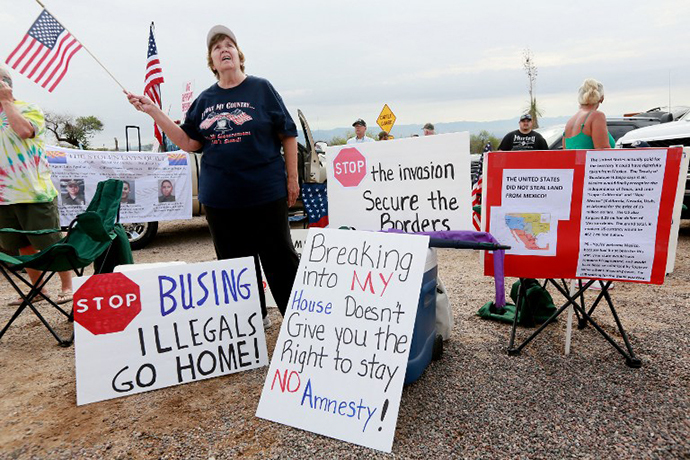 Anti-immigration activist Judy Lairmore holds a sign during a protest along Mt. Lemmon Road in anticipation of buses carrying illegal immigrants on July 15, 2014 in Oracle, Arizona. (AFP Photo / Getty Images / Sandy Huffaker)