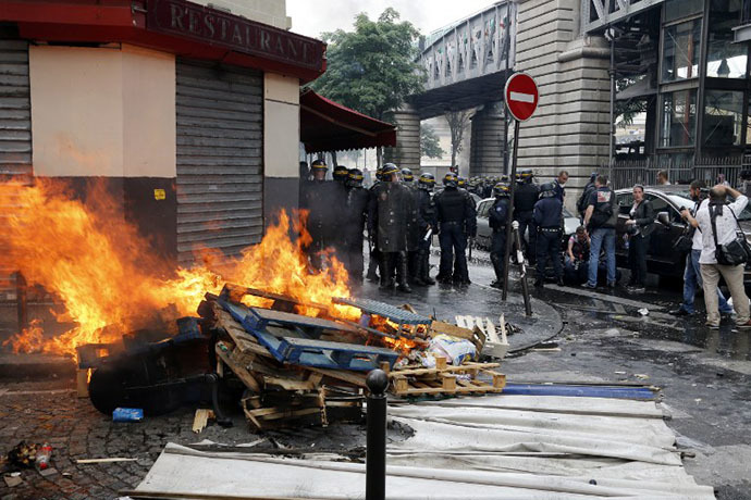French riot police officers stand by burning pallets near the aerial metro station of Barbes-Rochechouart, in Paris, on July 19, 2014. (AFP Photo / Francois Guillot)