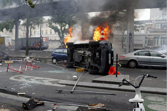 Burned vehicles owned by Paris public services are seen by the aerial metro station of Barbes-Rochechouart, in Paris, on July 19, 2014. (AFP Photo / Francois Guillot)