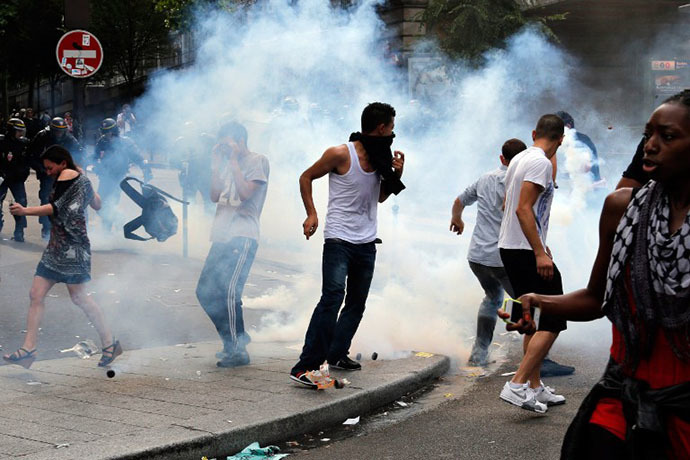 Protesters run to avoid tear gas near the aerial metro station of Barbes-Rochechouart, in Paris, on July 19, 2014. (AFP Photo / Francois Guillot)