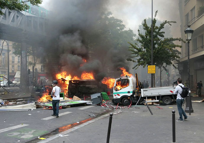 Protesters stand next to burning Paris public transport operator RATP trucks during clashes near the Barbes-Rochechouart aerial metro station in Paris on July 19, 2014. (AFP Photo / Jacques Demarthon)