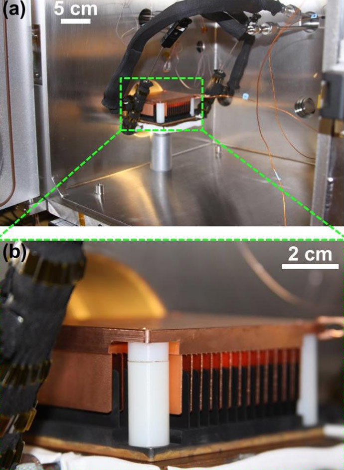 (a) Image of the experimental setup inside the chamber with a (b) magnified view of the cold-plate showing the interdigitated CuO and Cu combs sitting on top. (Screenshot from the article "Jumping-Droplet Electrostatic Energy Harvesting" by Nenad Miljkovic, Daniel J. Preston, Ryan Enright and Evelyn N. Wang, published in Applied Physics Letters, July 2014)